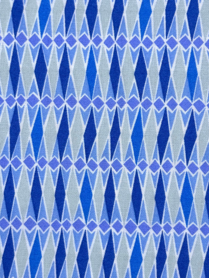 A close-up of a woven fabric with a repeating geometric pattern of blue and purple diamonds on a light gray background.