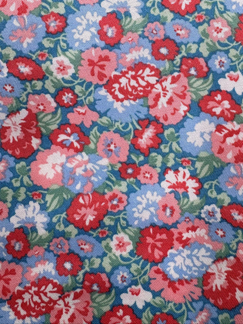 Floral fabric with red, pink, and blue flowers on a wooden surface