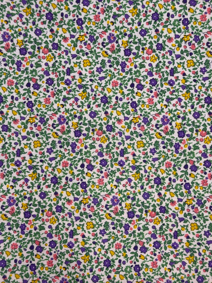 Floral patterned fabric with small flowers in various colors on a green background