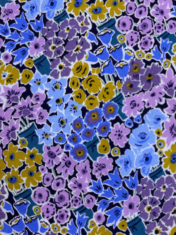 Floral fabric with purple, blue, and yellow flowers on a wooden surface