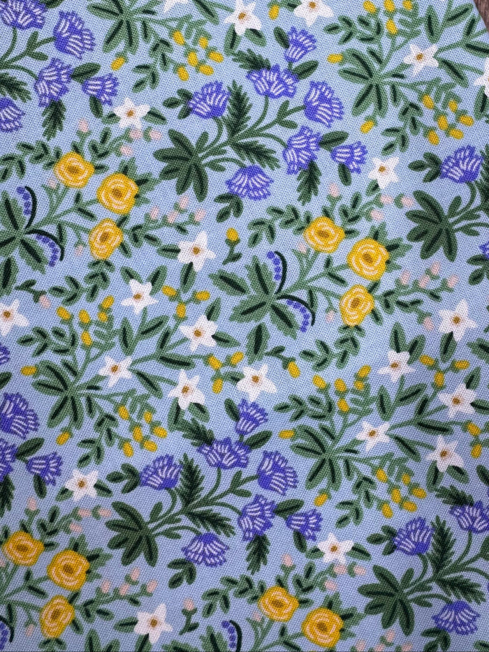 Floral fabric with yellow, blue, and green flowers on a wooden surface
