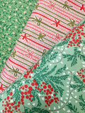 Three folded fabrics with holiday patterns displayed diagonally. The top-left fabric is green with small white stars and pine branches.