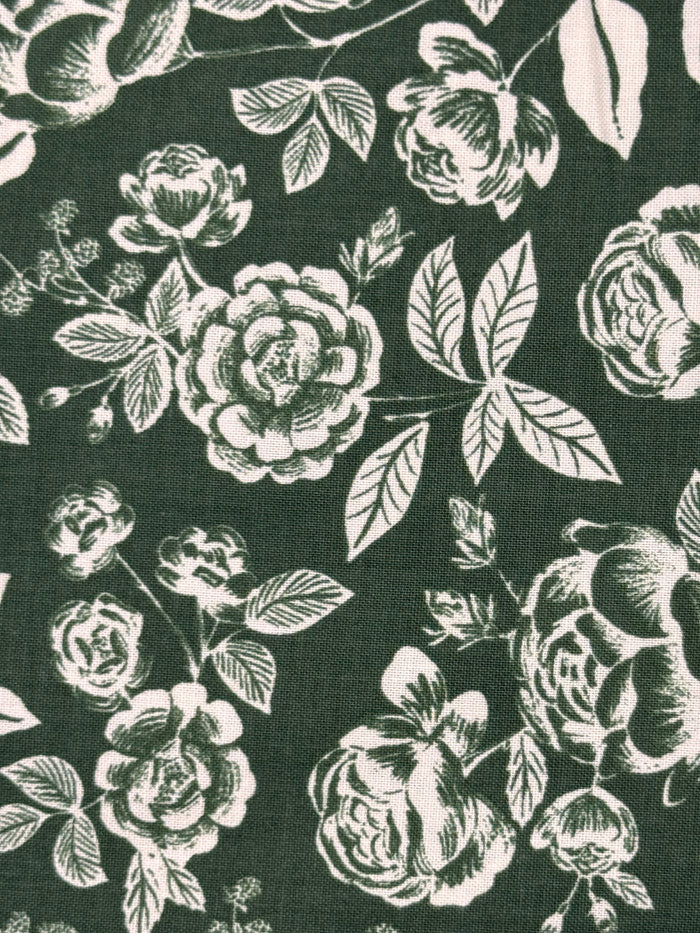 Dark forest green fabric with a white floral rose pattern, showing a close-up of the woven textile texture.