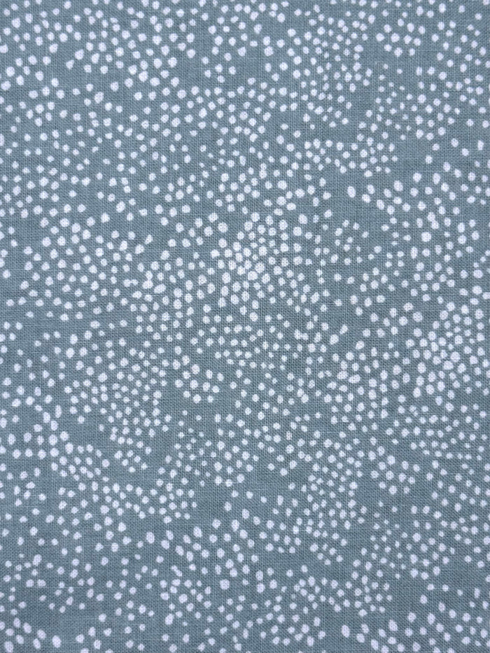 A close-up of a fabric or material swatch with a repeating white dotted pattern on a muted blue-sage background.